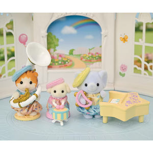Three toy figurines with musical instruments in a decorative setting with a rainbow and flowers.